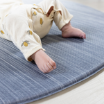 Soft edge of round play mat by totter and tumble little feet are comfortable on textured memory foam surface