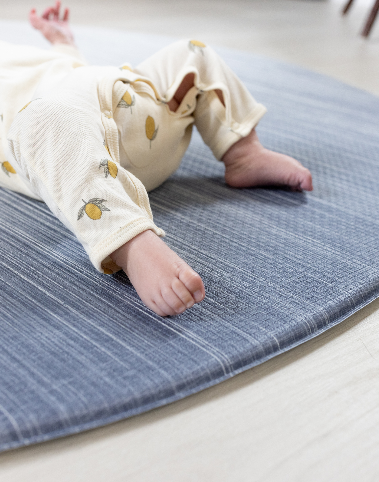 Soft edge of round play mat by totter and tumble little feet are comfortable on textured memory foam surface