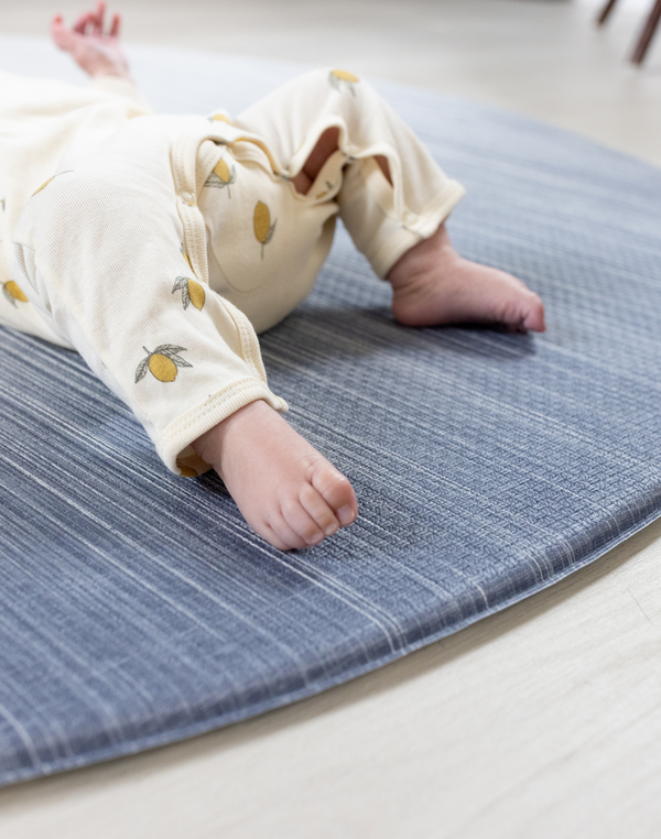 Soft edge of round play mat by totter and tumble little feet are comfortable on textured memory foam surface
