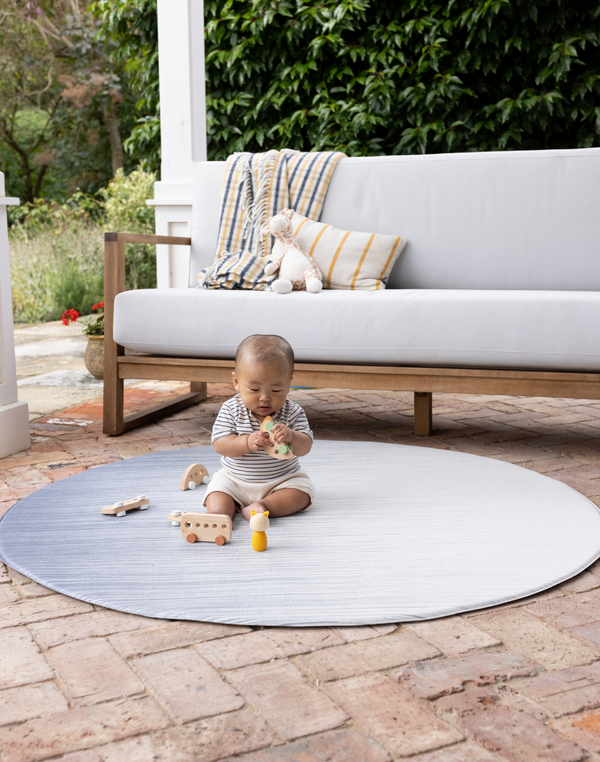 Baby sitting up on foam mat by totter and tumble in large round size ideal for unrolling on the patio in the warm weather for protection on the floor 