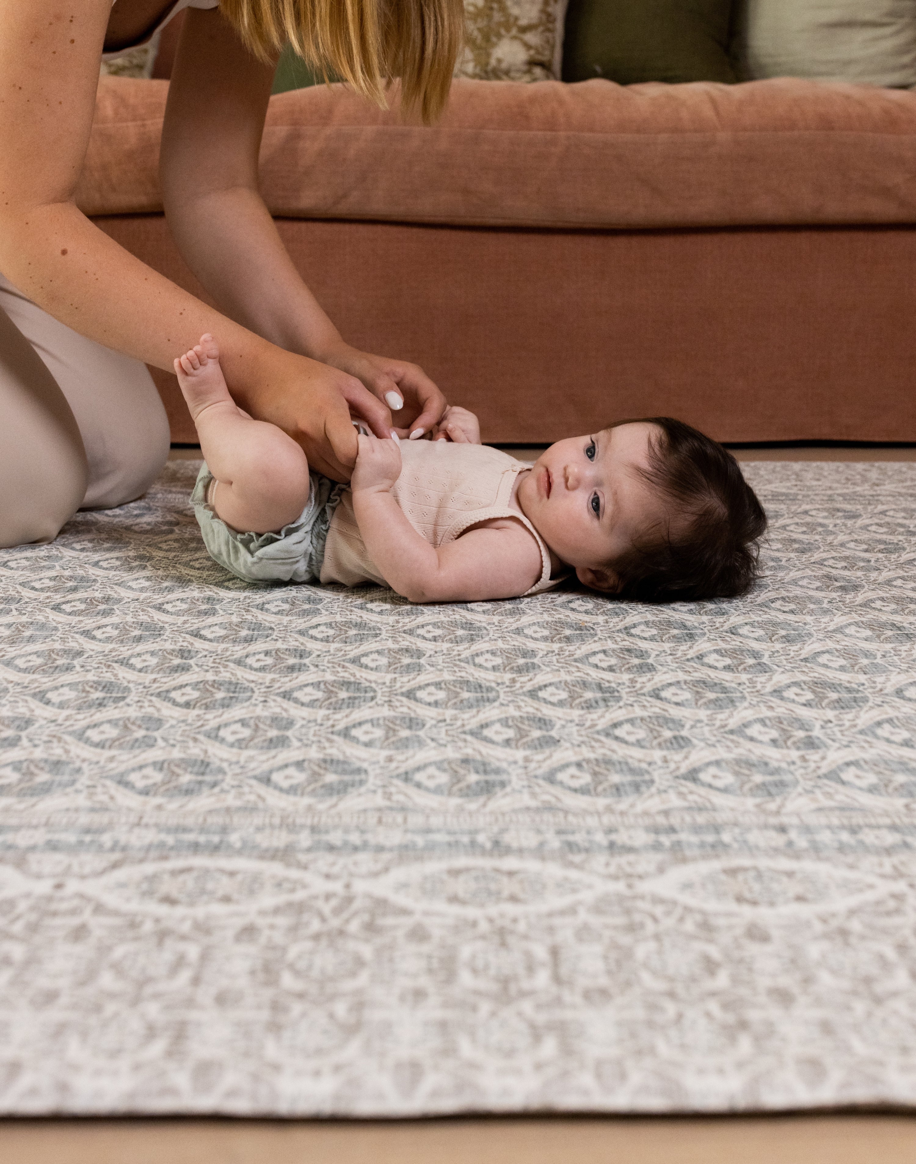 Baby lying on soft grey Totter & Tumble large playmat in stylish living room