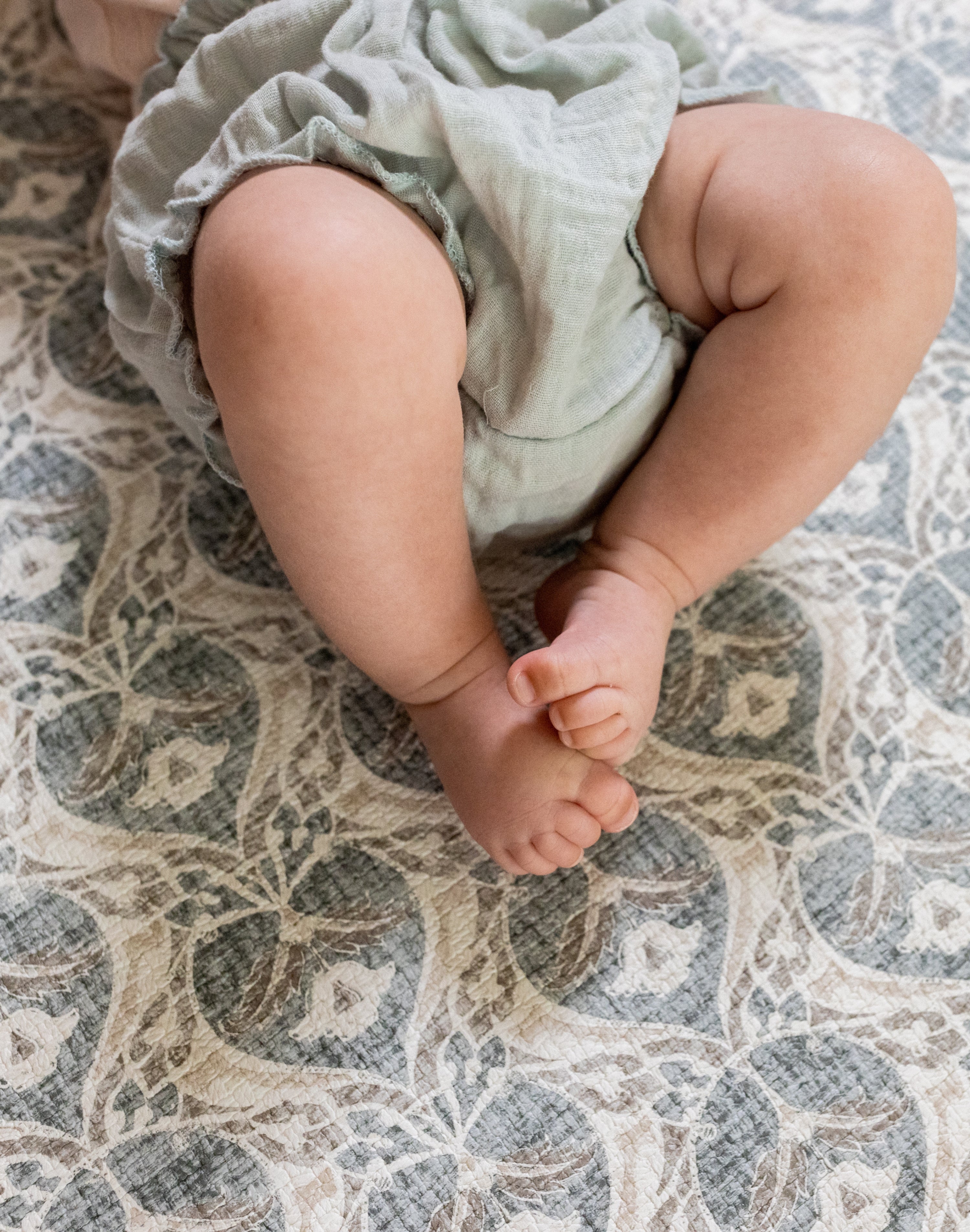 Baby's feet  lying on a soft grey textured playmat
