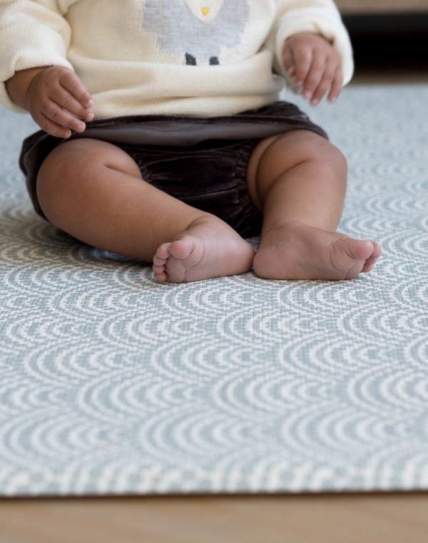 Little ones legs resting on soft baby play mat designed for support and stylish for family homes 