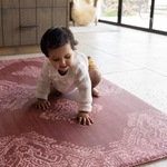 Baby crawls across red play mat the Merah with a beautiful handdrawn Batik inspired design thick memory foam protection ideal for tiled kitchen flooring