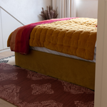 Stylish red runner mat sits stylishly alongside a beautiful upholstered bed providing support when climbing in and out of bed