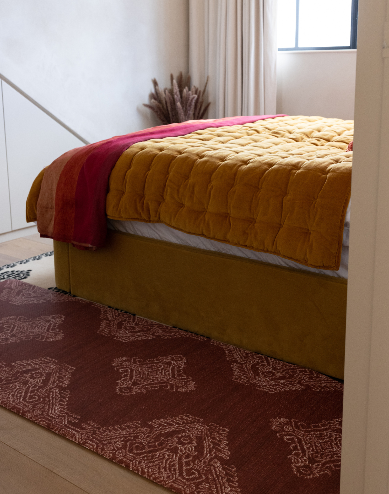 Stylish red runner mat sits stylishly alongside a beautiful upholstered bed providing support when climbing in and out of bed