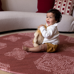 Cute baby plays with soft toy on protective red round play mat ideal for play corners in the home