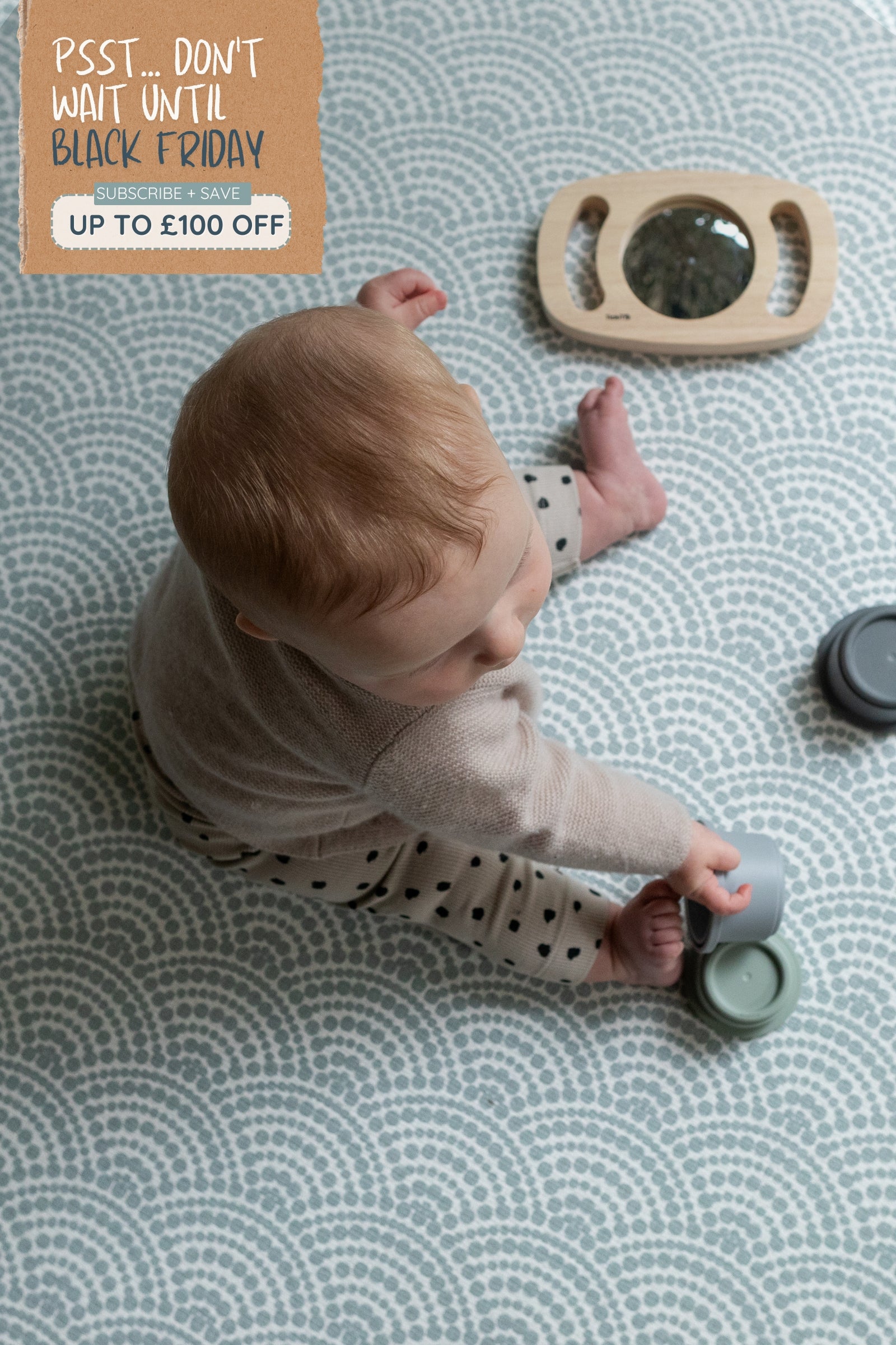 Sign that reads Don't wait until Black Friday for up to £100 off playmats. Overhead picture of a child playing on a soft patterned crawling mat.