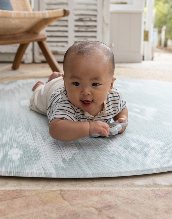 Adorable baby enjoys tummy time on thick and large baby round play mat perfect for floor time for the whole family 
