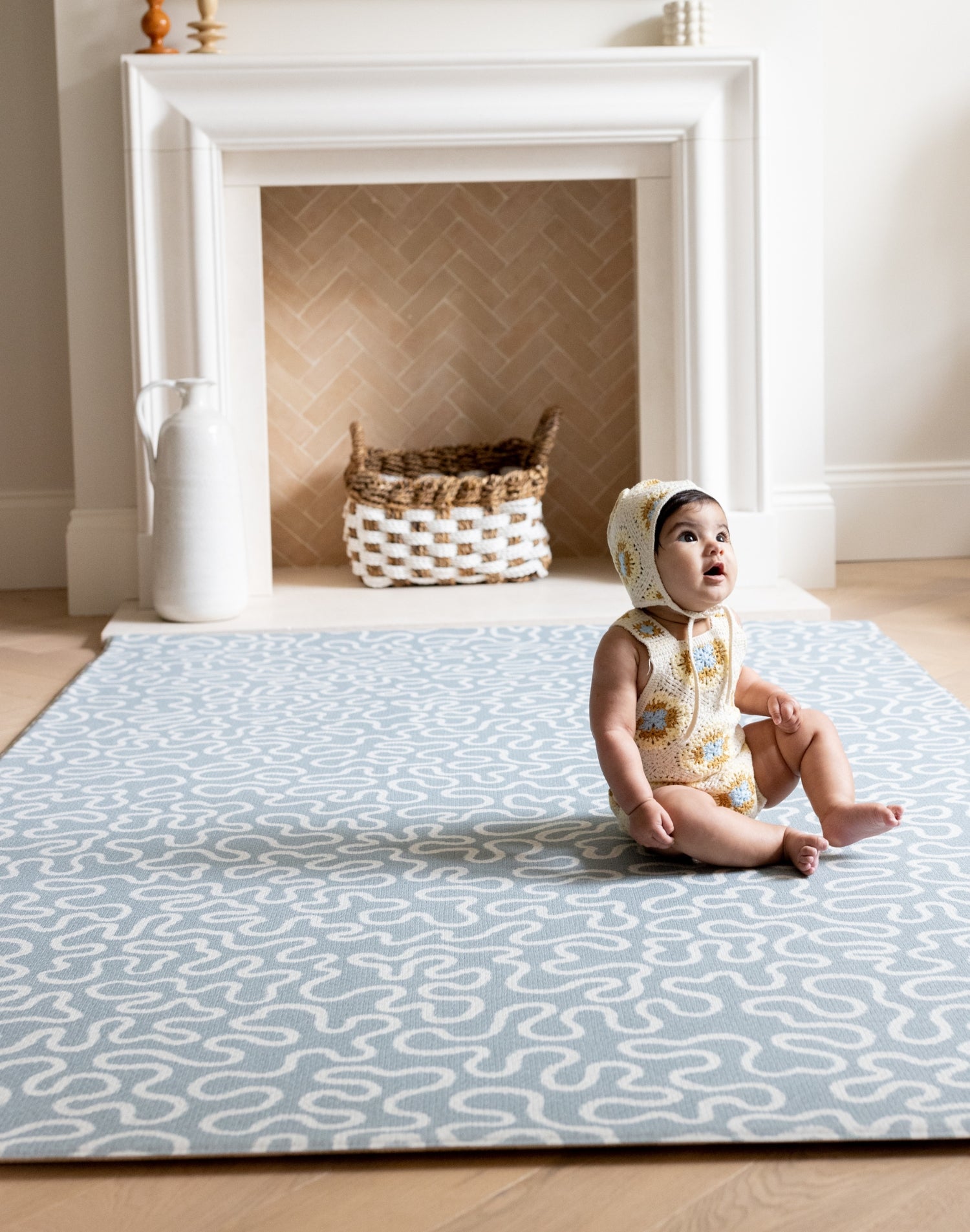 Baby sits on The Pembroke, a calming sea foam blue rug, perfect as a large play mat for crawling baby.