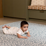 Newborn enjoying tummy time on The Pembroke, a kids playmat with soft, calming sea foam hues.