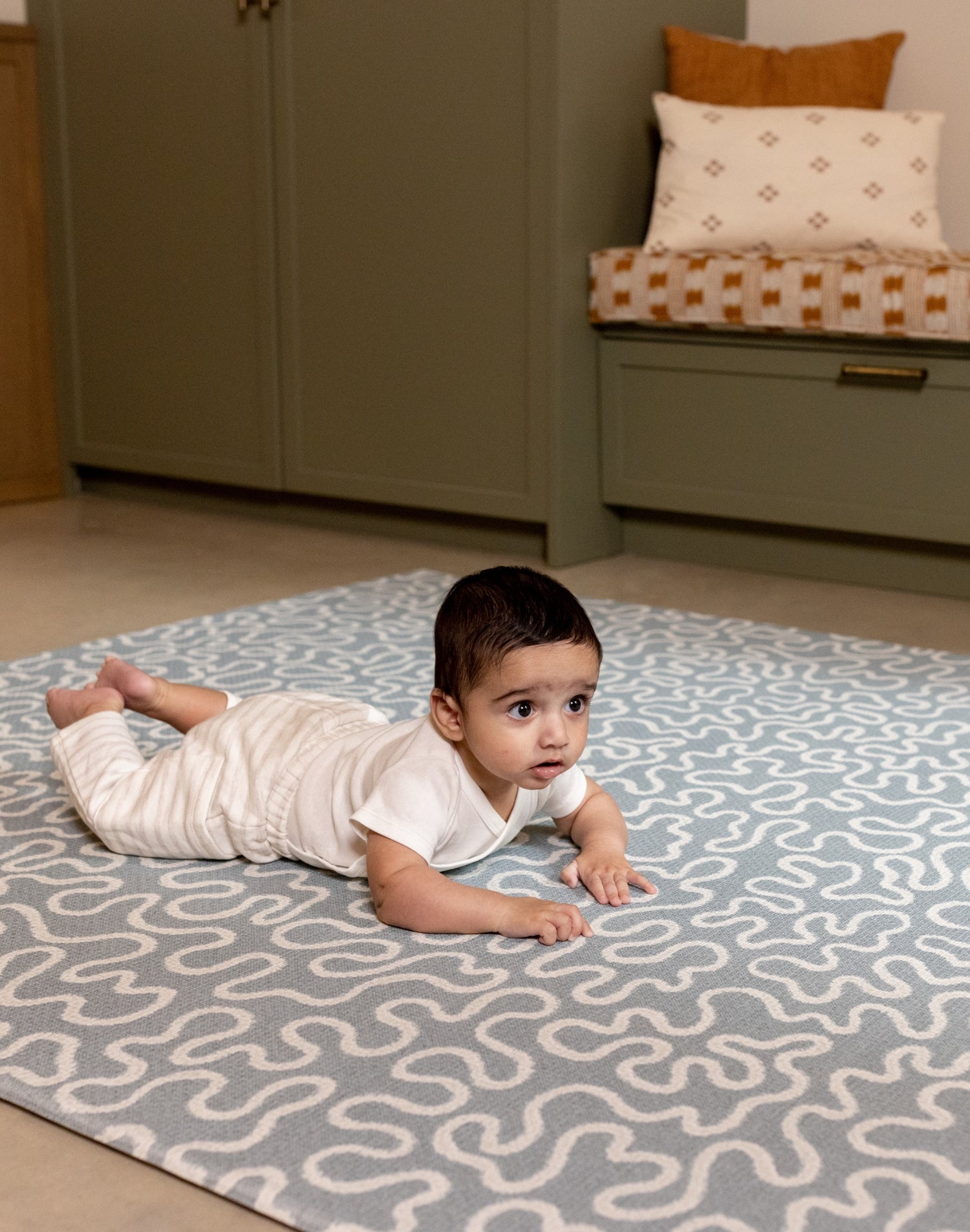 Newborn enjoying tummy time on The Pembroke, a kids playmat with soft, calming sea foam hues.