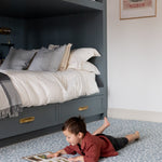 Child reading on a Totter + Tumble play mat, a soft and safe playmat for cosy corners and quiet play in small spaces.