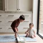 Siblings on The Pembroke, a wild river-inspired playmat that’s ideal as a wipeable baby mat or playing mat for kids.