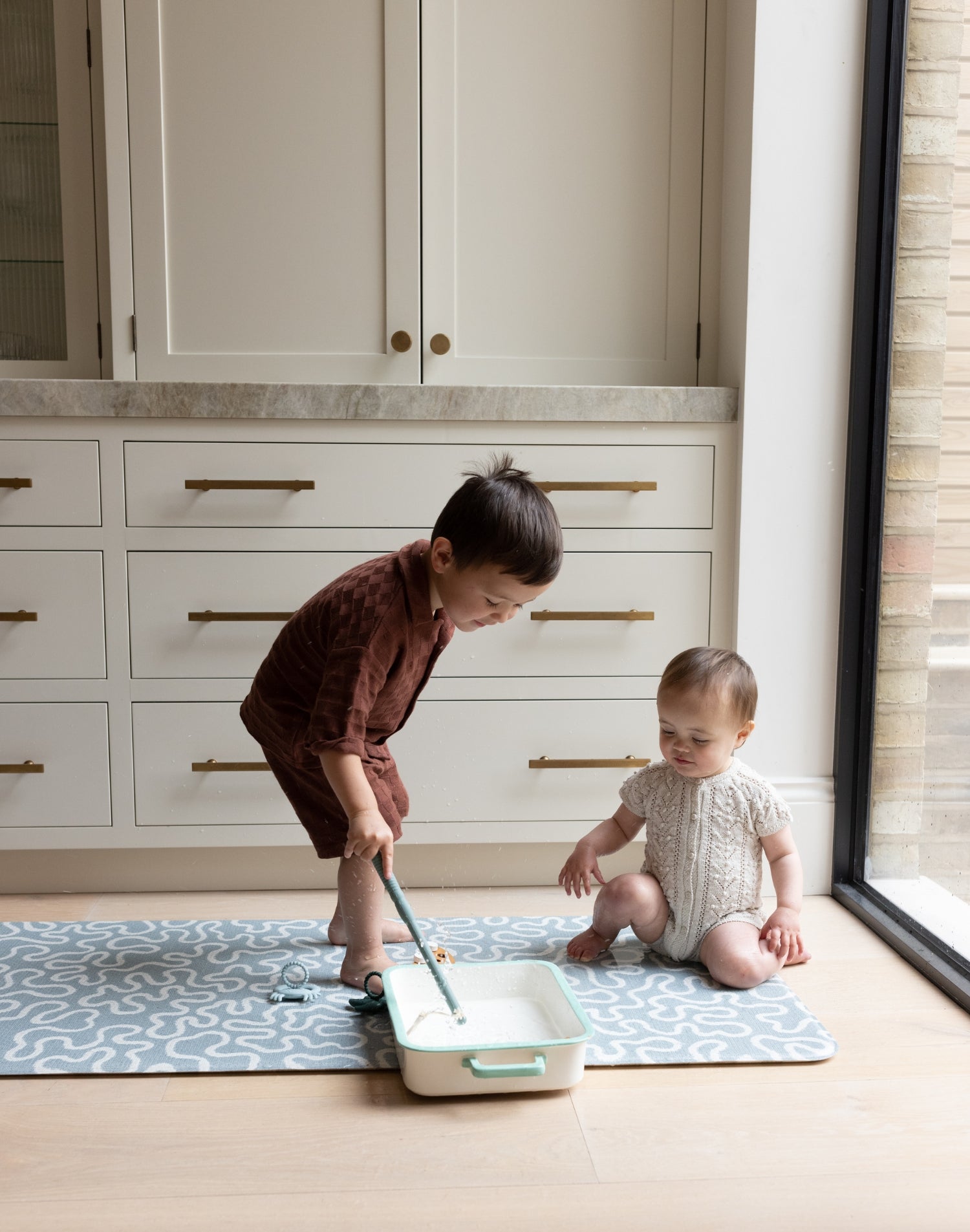 Siblings on The Pembroke, a wild river-inspired playmat that’s ideal as a wipeable baby mat or playing mat for kids.