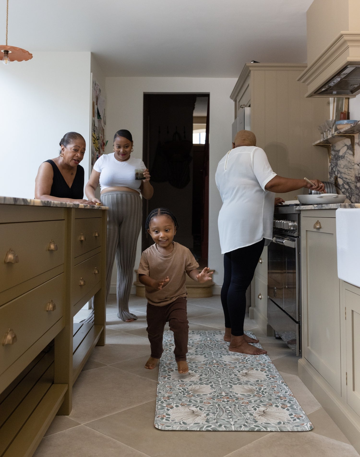 family gathering in the kitchen with baby and mother using totter and tumble play runner to cushion their feet