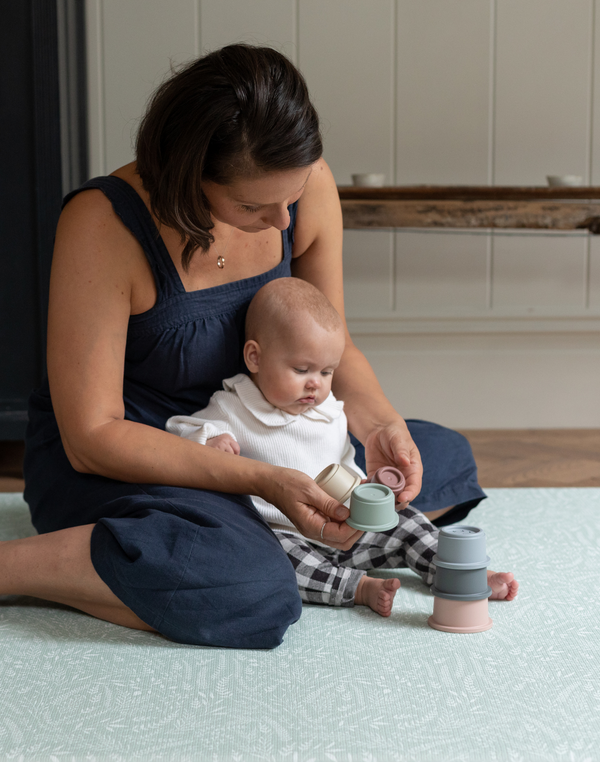 Mother and baby enjoy play time on the rambler green playmat with a subtle botanical print reminiscent of english meadows 