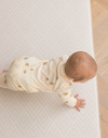 Baby crawling across neutral textured play mat that offers supports through the developmental stages 