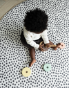 Baby plays with wooden stacking toy supported on the large round baby mat by totter and tumble