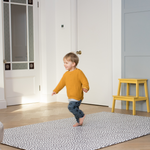 Little boy runs across the extra large playmat by totter and tumble with a polka dot design 