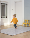 Little boy runs across the extra large playmat by totter and tumble with a polka dot design 