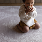 Baby kneels on memory foam play mat The Sepi to support play time and floor time activities the delicate design complements modern boho family interiors 