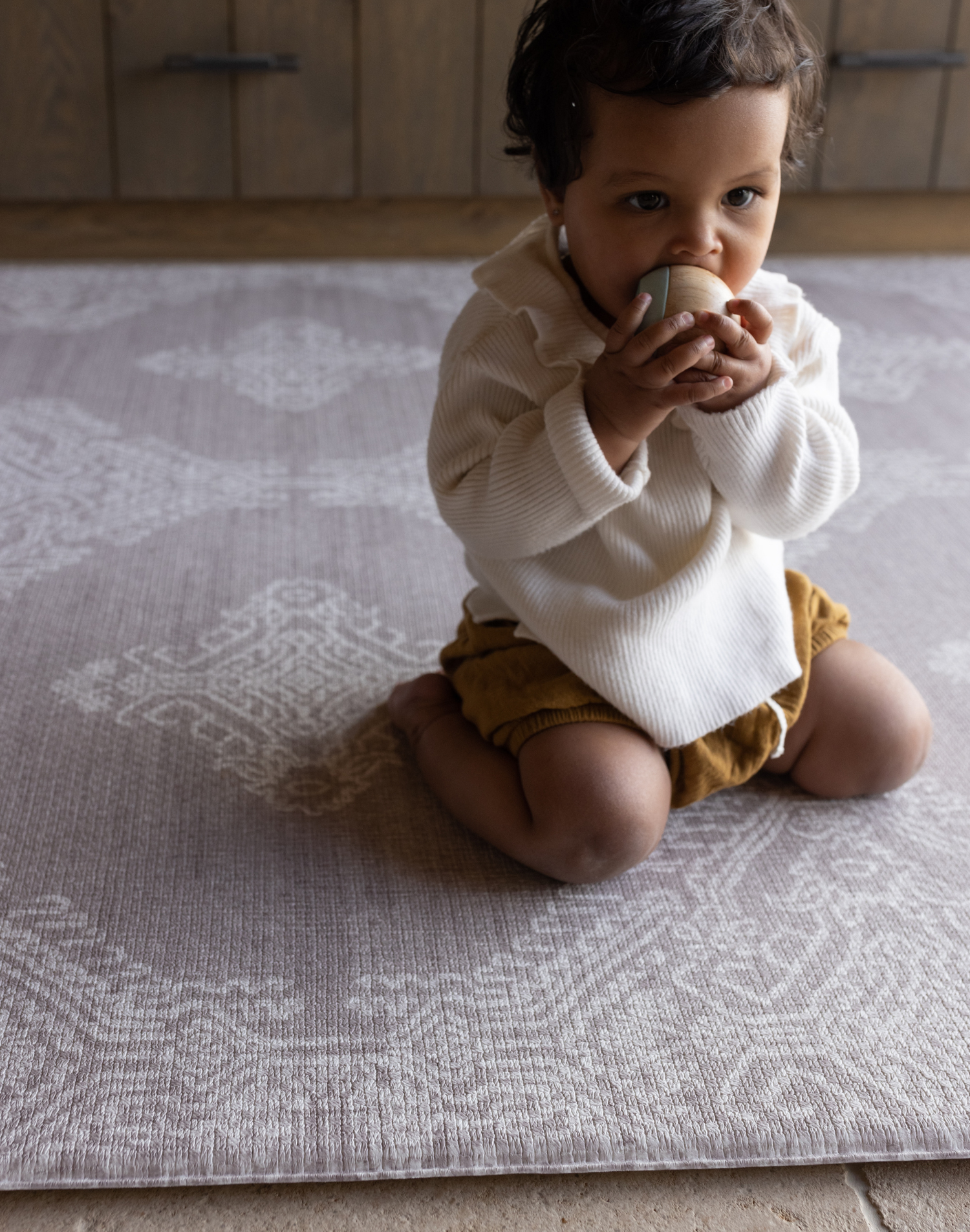 Baby kneels on memory foam play mat The Sepi to support play time and floor time activities the delicate design complements modern boho family interiors 