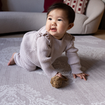 Baby crawls across supportive play mat with thick memory foam for ultimate protection and support the flexible grey design features a hand drawn Batik inspired pattern that has a textile aesthetic to complement modern interiors 