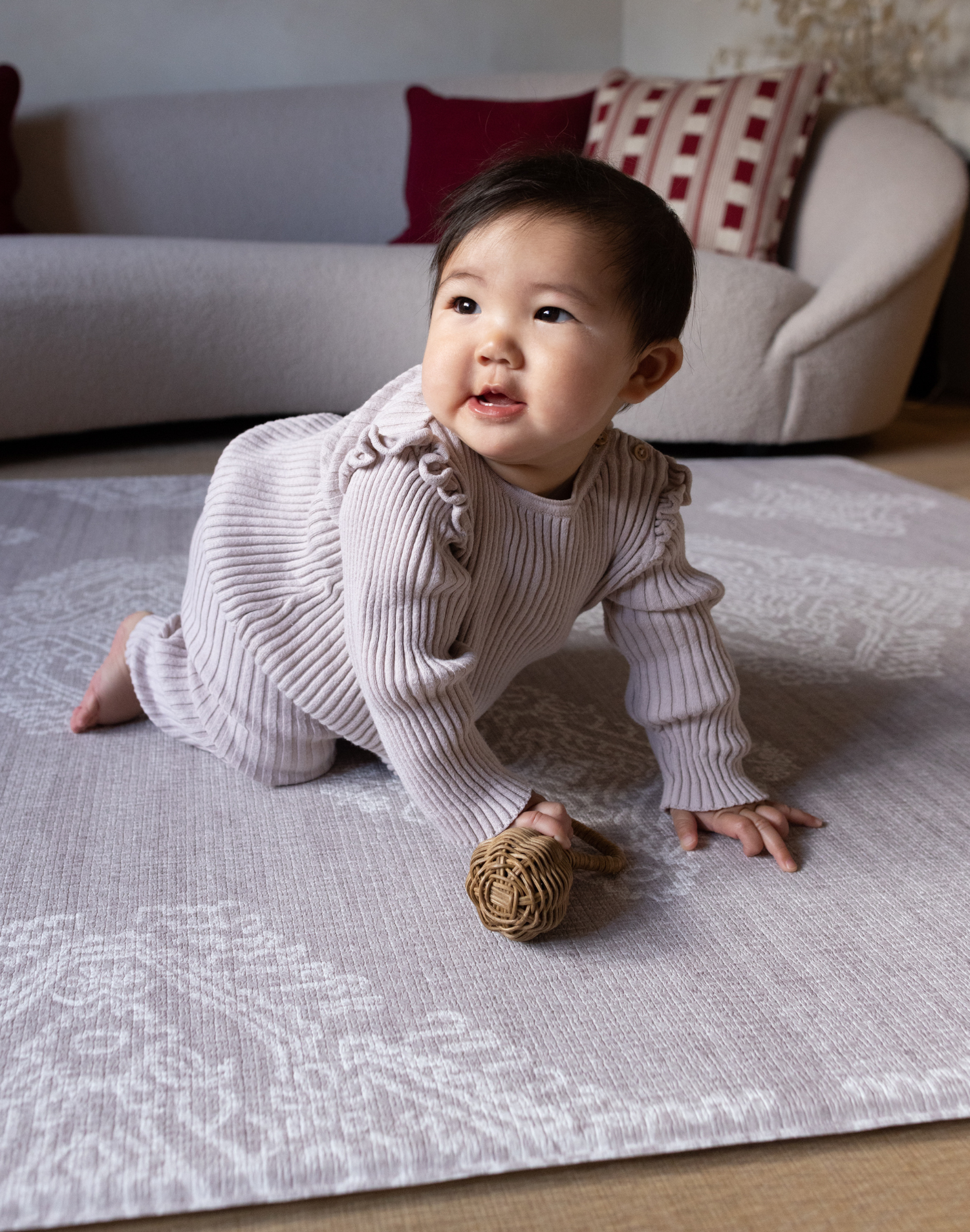 Baby crawls across supportive play mat with thick memory foam for ultimate protection and support the flexible grey design features a hand drawn Batik inspired pattern that has a textile aesthetic to complement modern interiors 