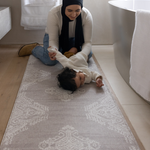 Mother changes baby girl on the large bathroom mat the sepi ideal as a kitchen mat and exercise mat in the home too with a gentle grey design to style seamlessly into modern family interiors 