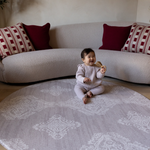 Baby sits unaided in comfort on the round sepi play mat with a gentle grey batik design that complements modern homes and thick memory foam to protect during wobbles and falls 