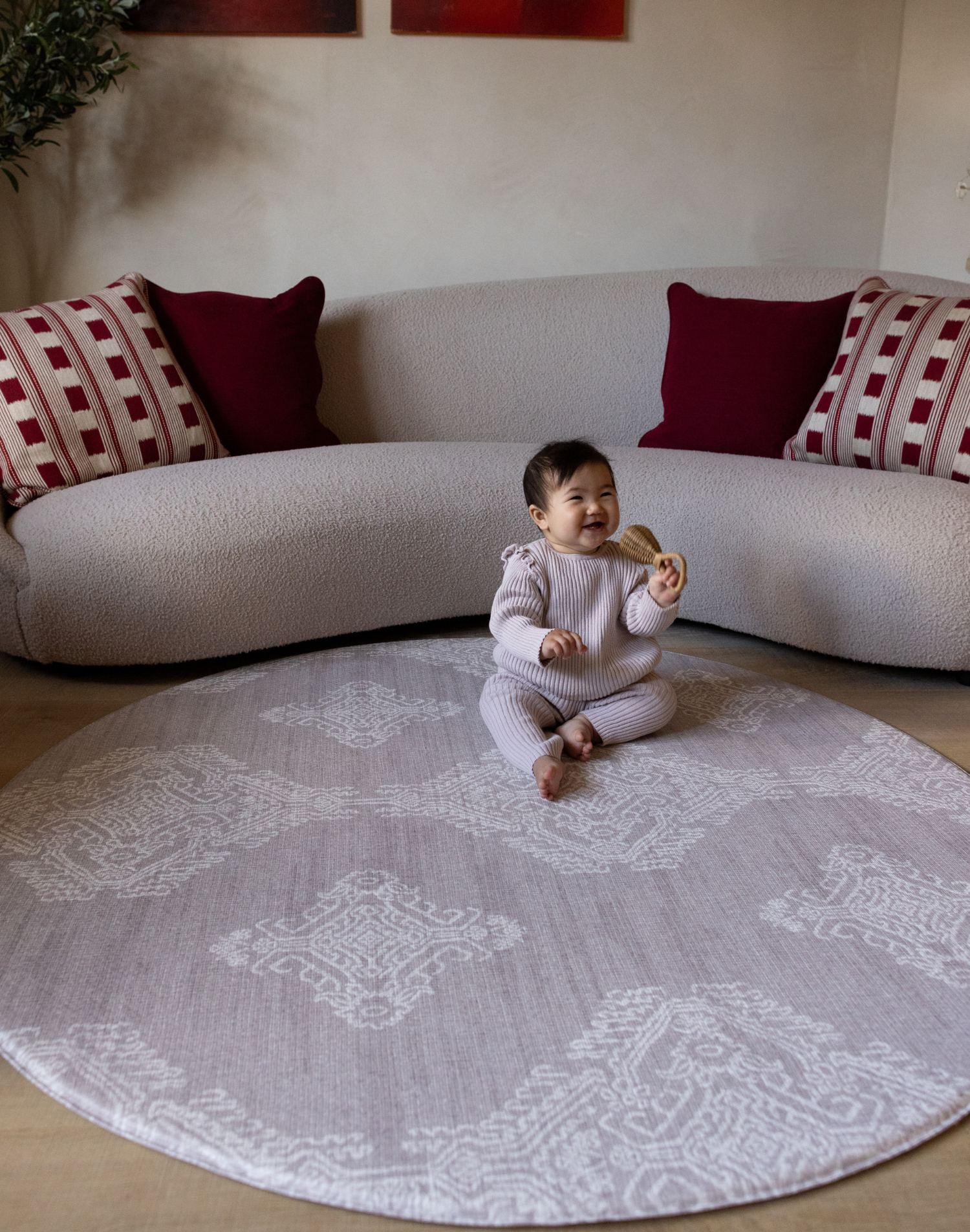 Baby sits unaided in comfort on the round sepi play mat with a gentle grey batik design that complements modern homes and thick memory foam to protect during wobbles and falls 