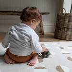 Little boy kneels on knee saving playmat with luxury memory foam for support 