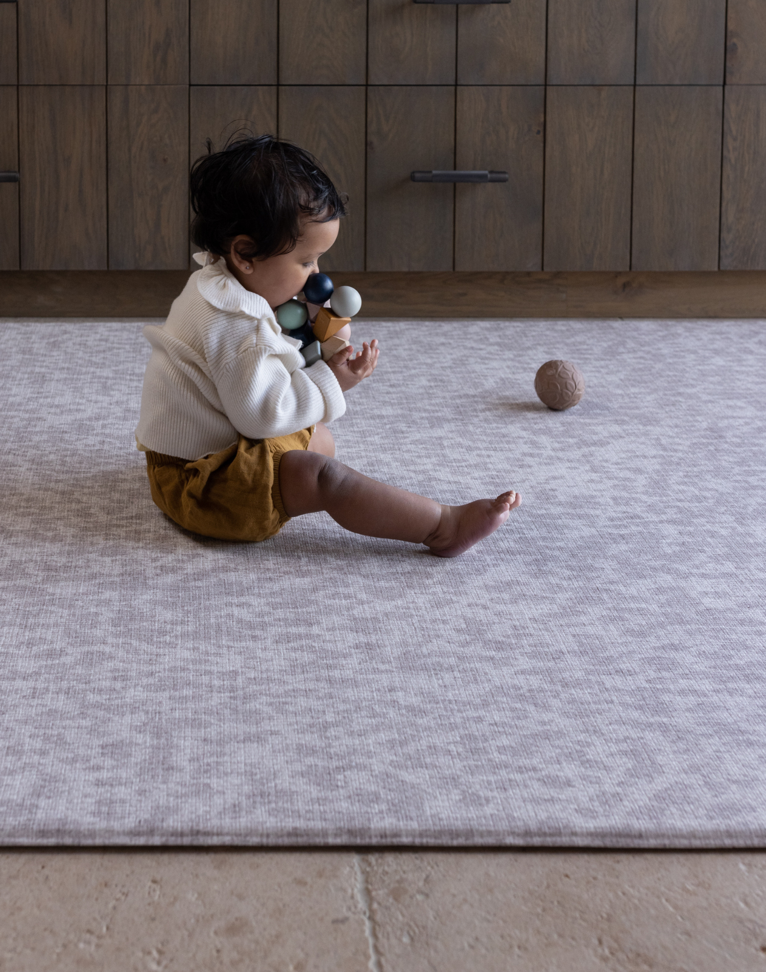 Baby girl plays on grey leopard print play mat which provides memory foam protection on hard tiled flooring for protection and peace of mind during floor play