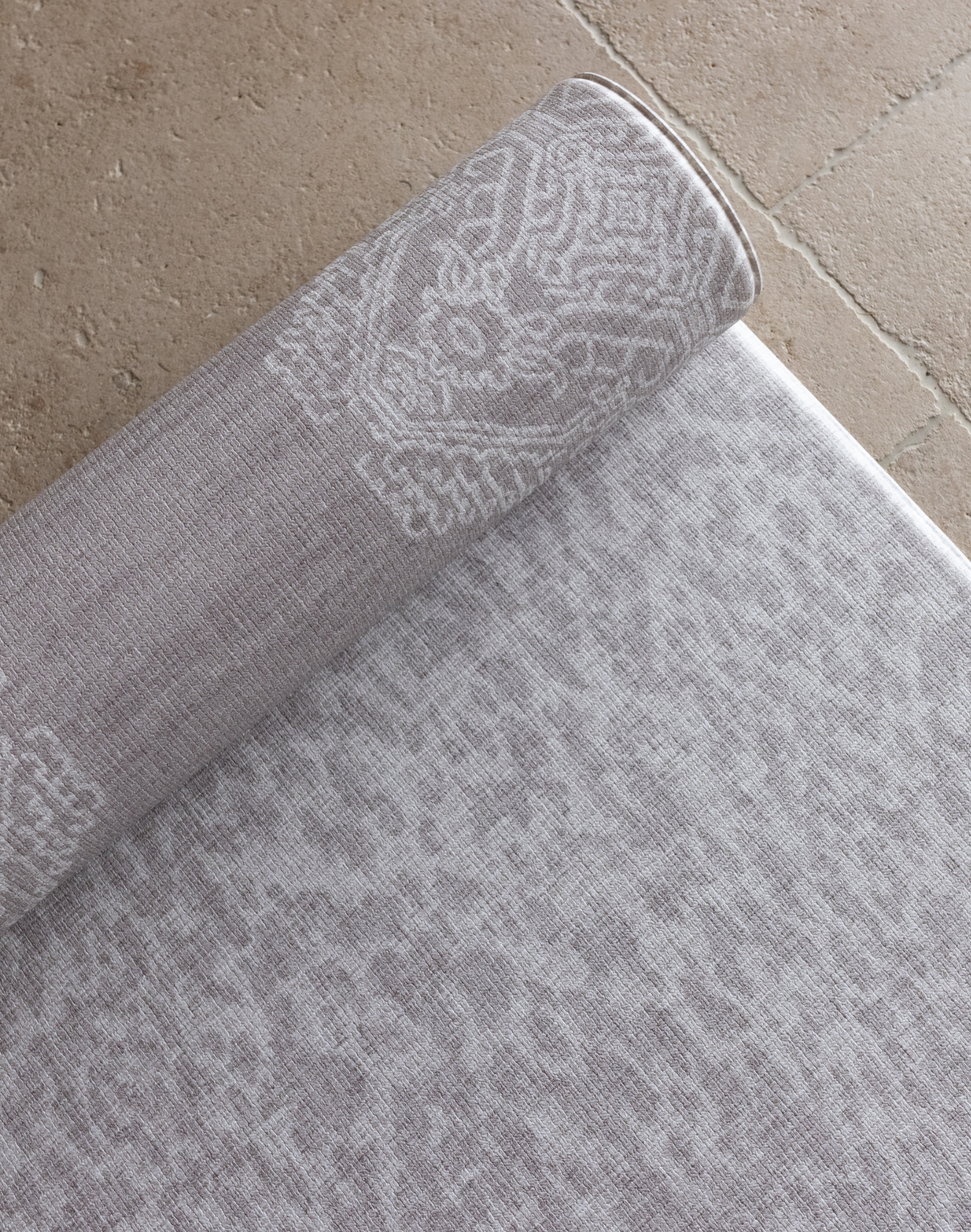 Close up of the grey animal print playmat with a textural batik inspired rug design on the rug unroll on hard wood tiled or carpeted flooring for support and comfort for the whole family 