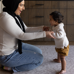 Baby girl stands on memory foam play mat supported by mother protective memory foam keeps baby and mother comfortable during play time and milestone development