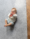 Baby plays with non toxic teething toy laying on comfortable play mat that keeps little ones off cold hard floors 