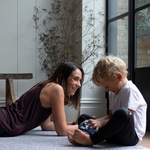 Exercising lady and boy giggle on the floor supported by leopard print playmat by totter and tumble 