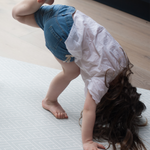 Little girl stretches out on mouldable playmat with thick luxury memory foam and a grey pattern 