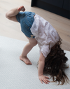 Little girl stretches out on mouldable playmat with thick luxury memory foam and a grey pattern 