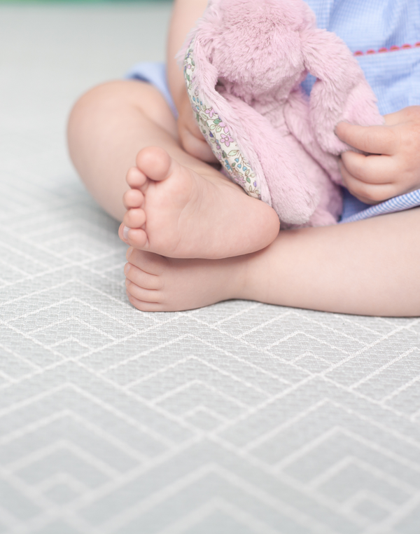 Baby feet rest on foam playmat providing support and protection for sitting