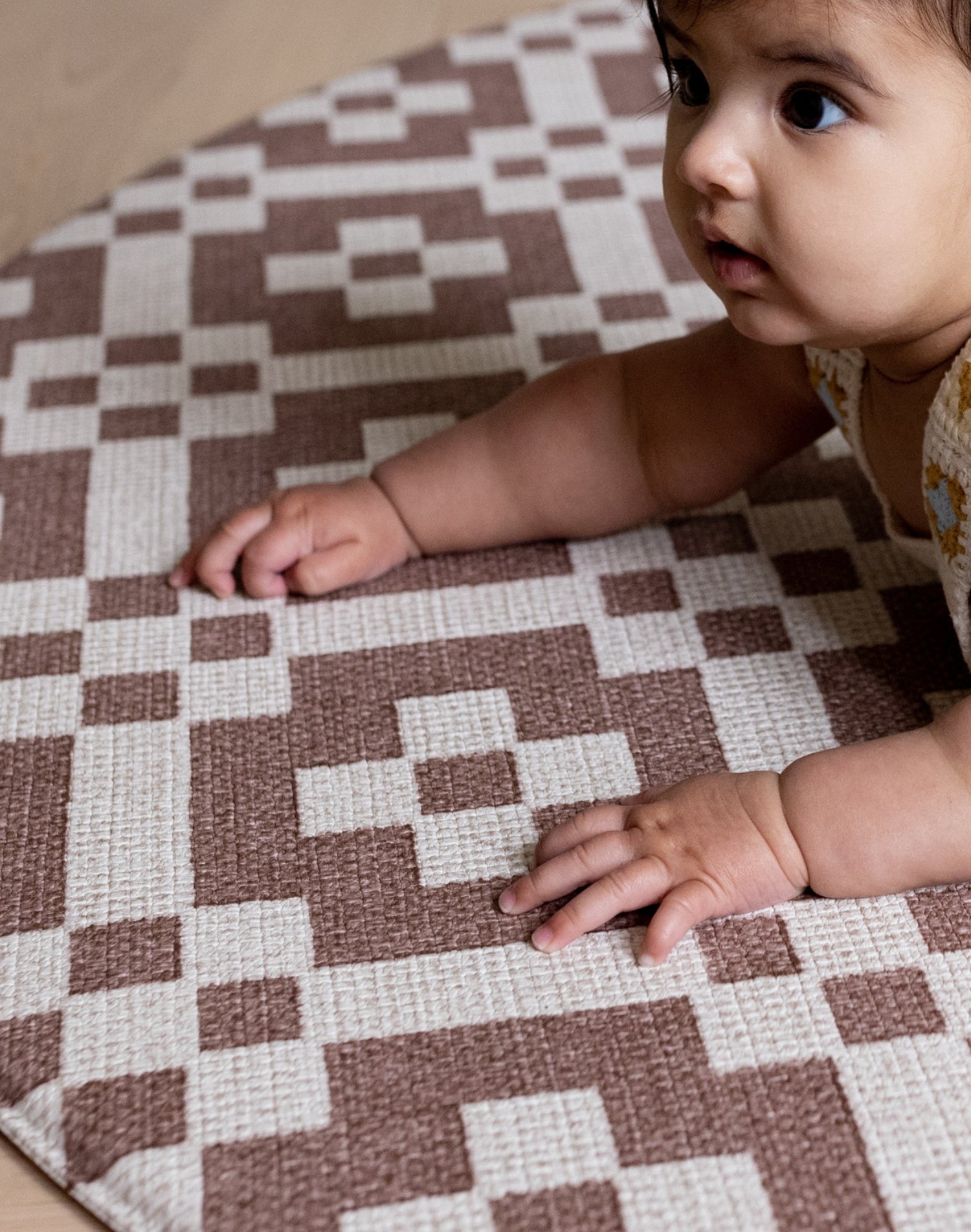 A baby crawls on a Totter + Tumble tummy time mat from the summer 2025 baby collection
