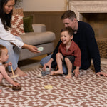 Family playing with toys on an extra large playmat for toddlers in a chic neutral living room.