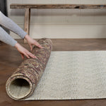 Person unrolling a patterned playmat on a wooden floor