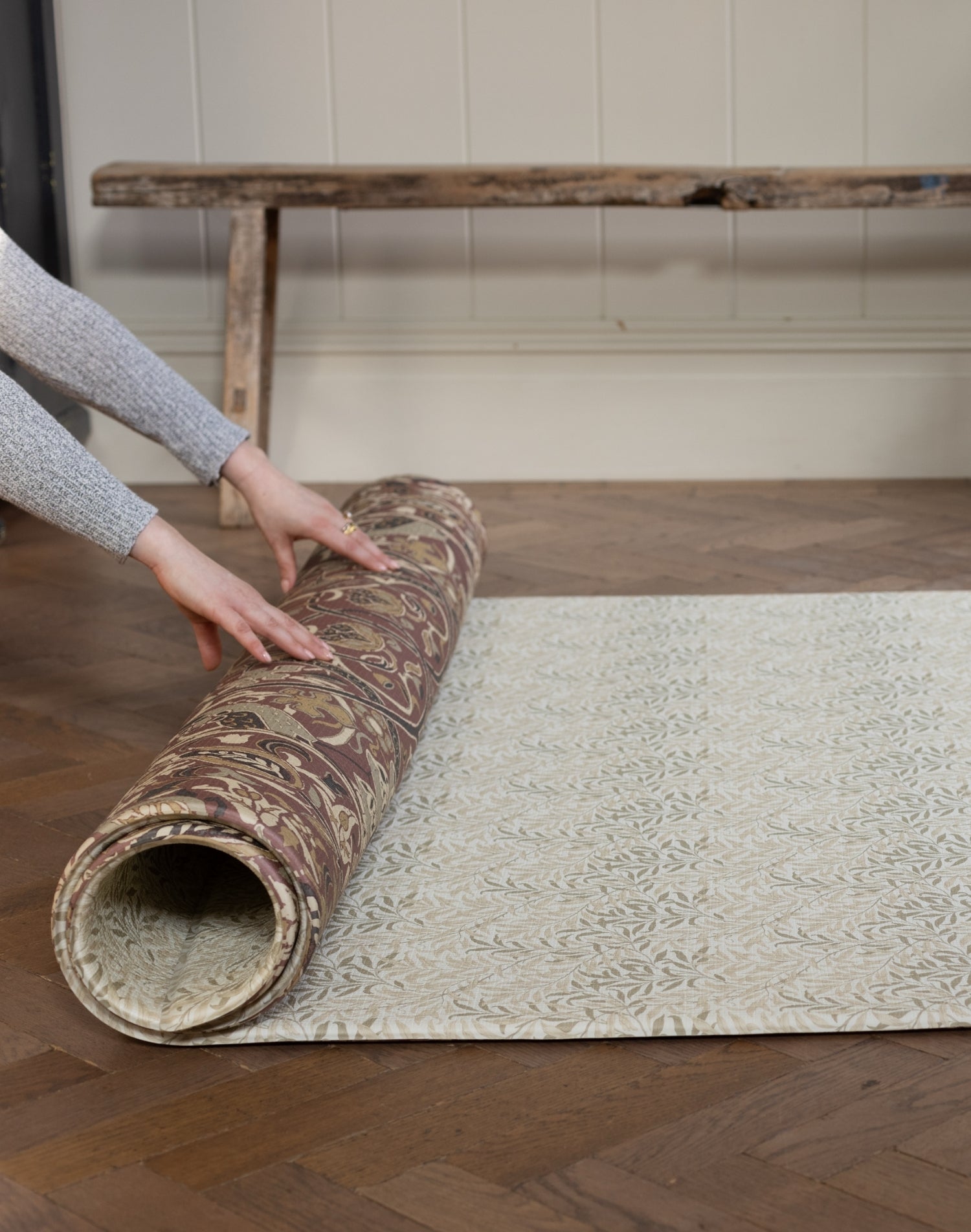Person unrolling a patterned playmat on a wooden floor
