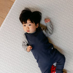 A baby laying comfortably on a thick, safe, non toxic memory foam playmat from totter and tumble