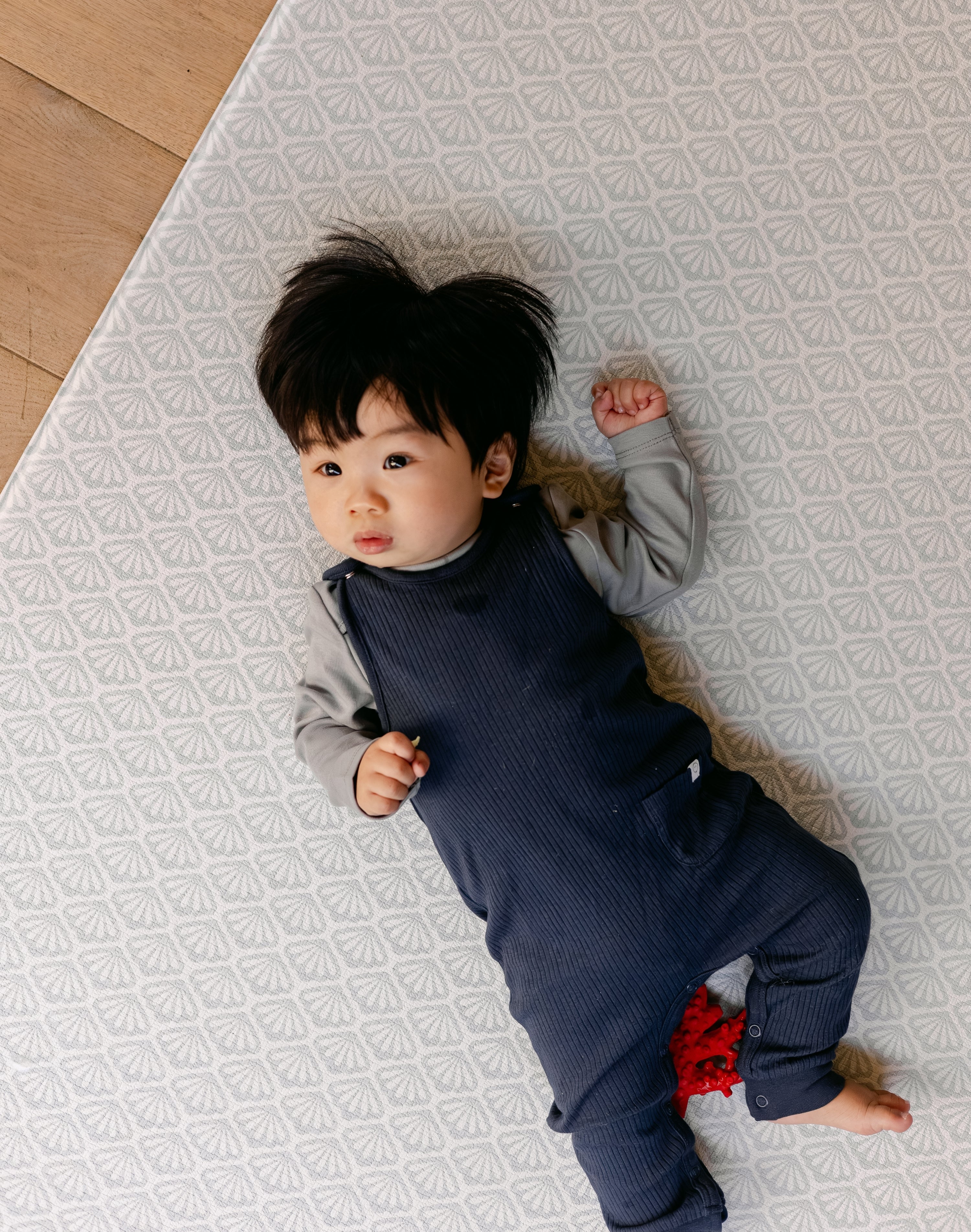 A baby laying comfortably on a thick, safe, non toxic memory foam playmat from totter and tumble