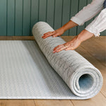 person unrolling the reversible beachcomber shell design playmat from totter and tumble