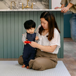 A woman sat with a baby on a thick memory foam beachcomber playmat 
