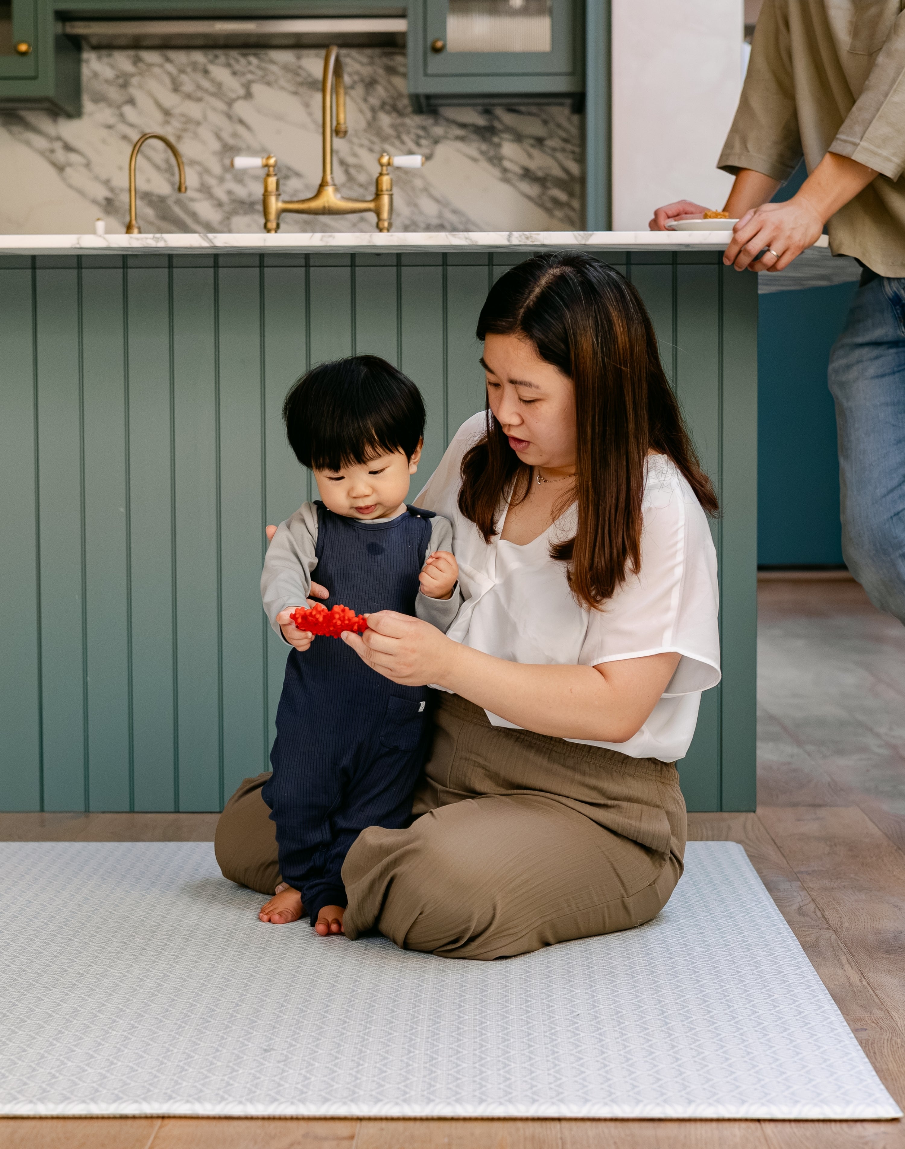 A woman sat with a baby on a thick memory foam beachcomber playmat 
